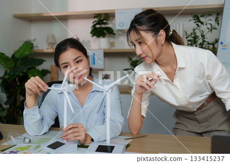 Collaborative Strategy. Women discussing wind turbine models and ESG initiatives in office. 133415237