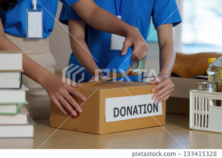 Packing Donations. Volunteers sealing boxes for a food donation drive. 133415328