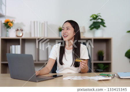 Financial Empowerment. Young woman managing personal finances with credit card and laptop. 133415345