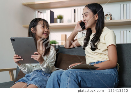 Joyful Interaction. Mother and daughter sharing smiles while using devices. 133415350