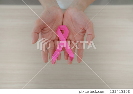 Breast cancer awareness. Woman holding pink ribbon in hands to promote health advocacy. 133415398