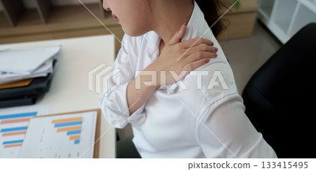 Office worker experiencing shoulder pain during work hours Office worker experiencing shoulder pain during work hours 133415495