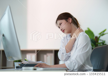 Posture Awareness. Young woman experiencing neck pain while working at computer. Posture Awareness. Young woman experiencing neck pain while working at computer. 133415511