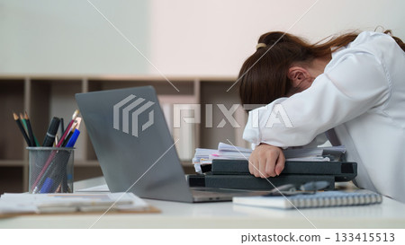 Exhausted office worker resting head on desk due to stress 133415513