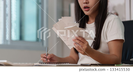 Concern. Woman analyzing financial papers at home office. 133415530