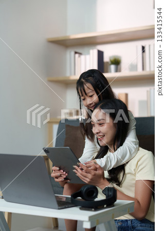 Sisterly Love. A girl joyfully shares a moment with her sister while using a tablet. Sisterly Love. A girl joyfully shares a moment with her sister while using a tablet. 133415544