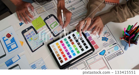 UI UX Design Collaboration. Close-up of designers selecting colors and refining wireframes. UI UX Design Collaboration. Close-up of designers selecting colors and refining wireframes. 133415551