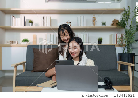 Family Connection. A mother and daughter share a digital moment while relaxing at home. Family Connection. A mother and daughter share a digital moment while relaxing at home. 133415621
