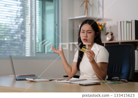 Financial stress. Woman expressing frustration while reviewing credit card statement at home office. 133415623