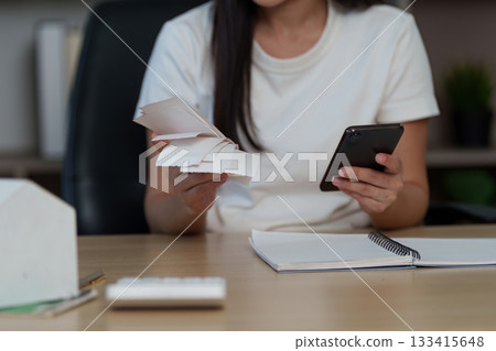 Organized Workspace. Young woman managing tasks with smartphone and notes. 133415648