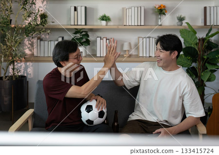 Father and son bonding over soccer, celebrating victory at home Father and son bonding over soccer, celebrating victory at home 133415724