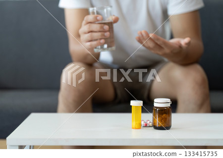 Health Awareness. Person considering medication options with water at home. Health Awareness. Person considering medication options with water at home. 133415735