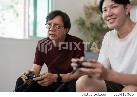 Father and Son Gaming Together. A joyful moment captured during a video game session. 133415809