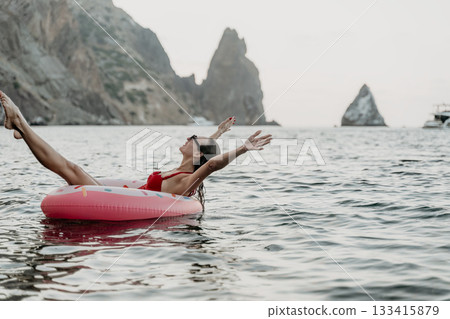 Woman, floating, sea. Happy woman on inflatable donut in the sea near cliffs on a summer vacation with copy space. 133415879