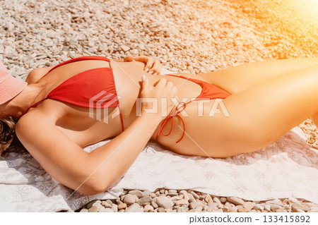 Woman Sunbathing Beach Red Bikini Sunbathing on a beach in a red bikini. 133415892