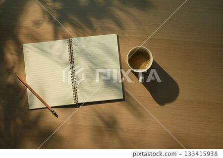 open notebook with blank pages next to cup of coffee with morning light open notebook with blank pages next to cup of coffee with morning light 133415938