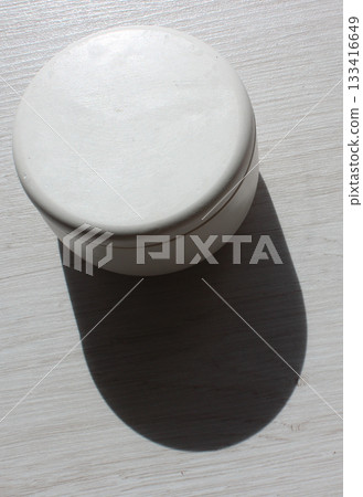 A perfect circle container casts a distinct shadow on a wooden board stock photo for vertical story A perfect circle container casts a distinct shadow on a wooden board stock photo for vertical story 133416649