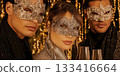 Closeup of three women in pearl masks against golden background 133416664
