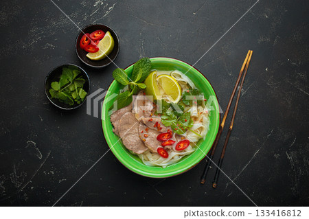 Vietnamese pho bo noodle soup beef lime asian bowl dinner black background top view 133416812