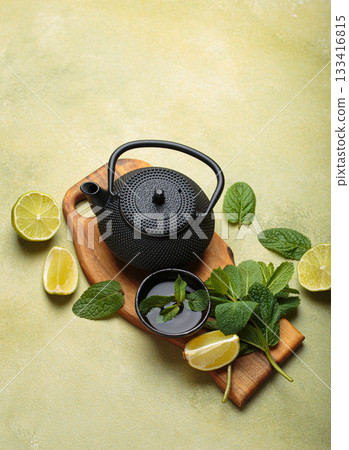 Black cast iron teapot refreshing mint lime herbal tea fresh relax healthy detox green background 133416815