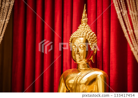 Brightness golden Buddha is sitting meditation in front of red scarlet curtain. 133417454