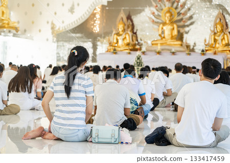 Portrait of people are meditating on Buddhist practices in the temple. People sit for meditation with peace and relax at temple or church and wearing white clothes. Portrait of people are meditating on Buddhist practices in the temple. People sit for meditation with peace and relax at temple or church and wearing white clothes. 133417459