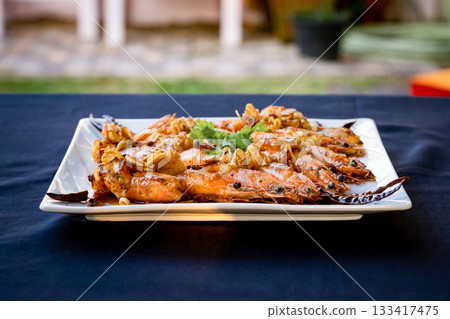 Crispy prawns in tamarind sauce in white square dish, sprinkle with glaze and top with fried shallots and coriander. It has perfect balance of crispy, spicy, and sweet flavors. Crispy prawns in tamarind sauce in white square dish, sprinkle with glaze and top with fried shallots and coriander. It has perfect balance of crispy, spicy, and sweet flavors. 133417475