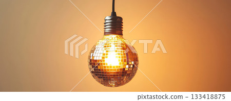 Disco ball light bulb against warm orange background, creative lighting concept 133418875