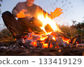 Man warming himself by a bonfire 133419129
