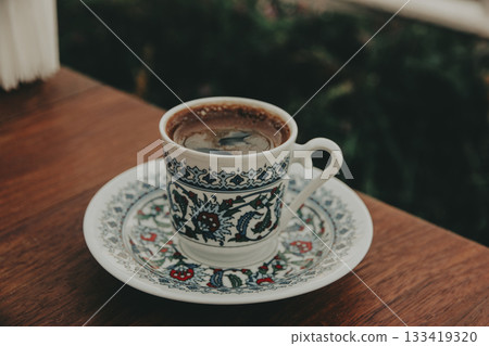Fragrant Turkish coffee in a traditional patterned porcelain small cup, served on a saucer. Rich culture of the East. Food and travel content. 133419320