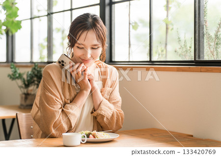一位年輕的亞洲女性在咖啡館吃義大利麵作為午餐 一位年輕的亞洲女性在咖啡館吃義大利麵作為午餐 133420769