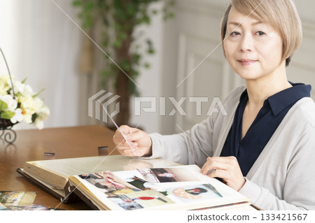 一位老婦人將孫輩和子女的照片放入相冊 一位老婦人將孫輩和子女的照片放入相冊 133421567