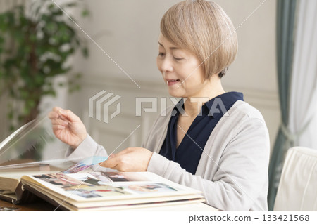一位老婦人將孫輩和子女的照片放入相冊 一位老婦人將孫輩和子女的照片放入相冊 133421568