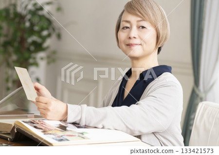 一位老婦人將孫輩和子女的照片放入相冊 一位老婦人將孫輩和子女的照片放入相冊 133421573