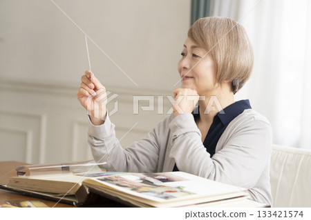 一位老婦人將孫輩和子女的照片放入相冊 133421574