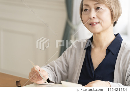 一位老婦人將孫輩和子女的照片放入相冊 133421584