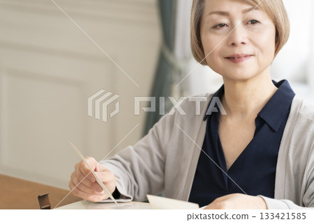 Senior woman putting photos of her grandchildren and children into an album Senior woman putting photos of her grandchildren and children into an album 133421585