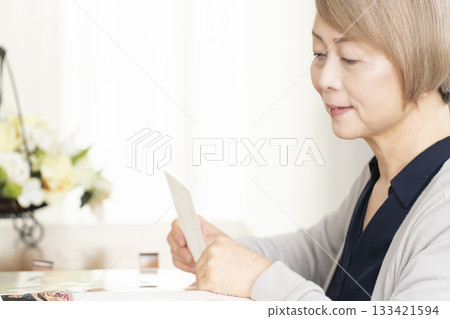 一位老婦人將孫輩和子女的照片放入相冊 一位老婦人將孫輩和子女的照片放入相冊 133421594