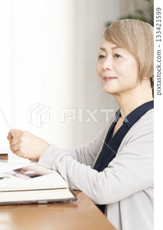 一位老婦人將孫輩和子女的照片放入相冊 133421599