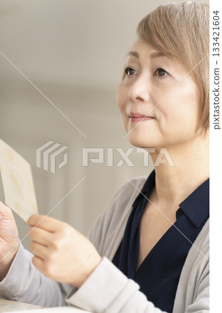 一位老婦人將孫輩和子女的照片放入相冊 一位老婦人將孫輩和子女的照片放入相冊 133421604