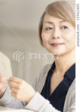 一位老婦人將孫輩和子女的照片放入相冊 133421605