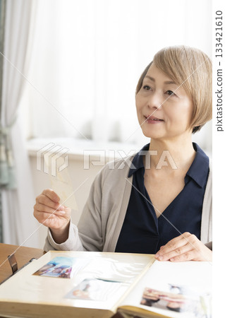 一位老婦人將孫輩和子女的照片放入相冊 133421610