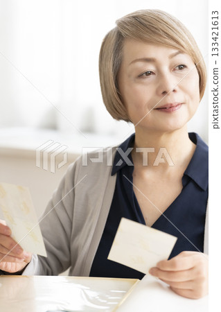 一位老婦人將孫輩和子女的照片放入相冊 133421613