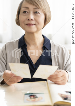 一位老婦人將孫輩和子女的照片放入相冊 133421617