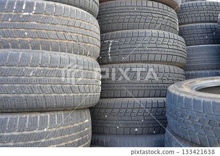 A pile of worn, slip-resistant, cracked discarded tires 133421638