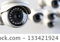 Close up view of a white electronic surveillance device with many circular lights. Multiple similar observation systems are blurry in the bright background. 133421924