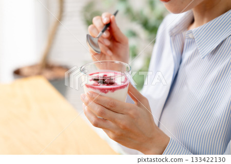 Woman eating yogurt 133422130