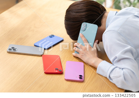 A woman making a phone call while looking at her smartphone A woman making a phone call while looking at her smartphone 133422505