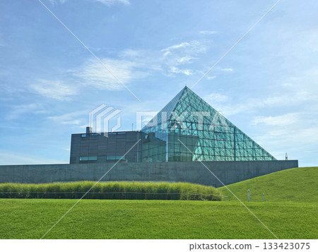 Modern architectural building with glass facade and geometric design under a blue sky	 133423075