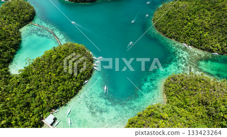 Shallow sea with coral reef and boats between green forest islands under bright light. Siargao, Philippines. Sugba Blue Lagoon. 133423264